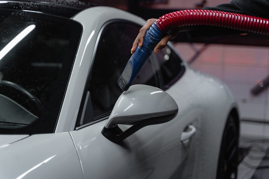 Detailer carefully vacuuming and cleaning the interior of a luxury vehicle